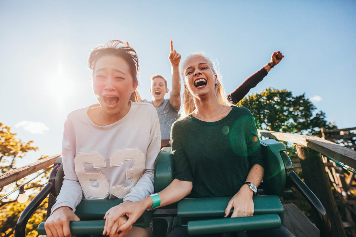 Enthusiastic young friends riding amusement park ride