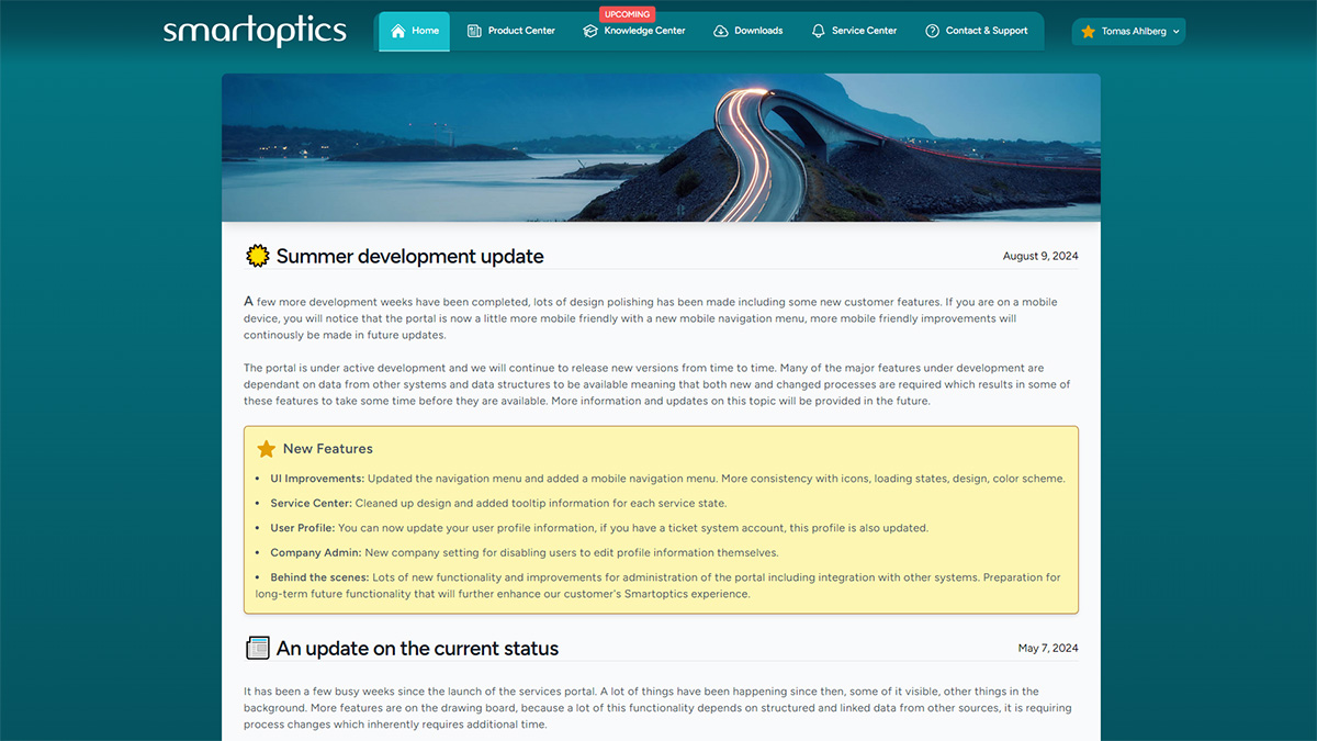 Smartoptics portal page showing a summer development update, new features list, navigation menu, and a scenic bridge image.