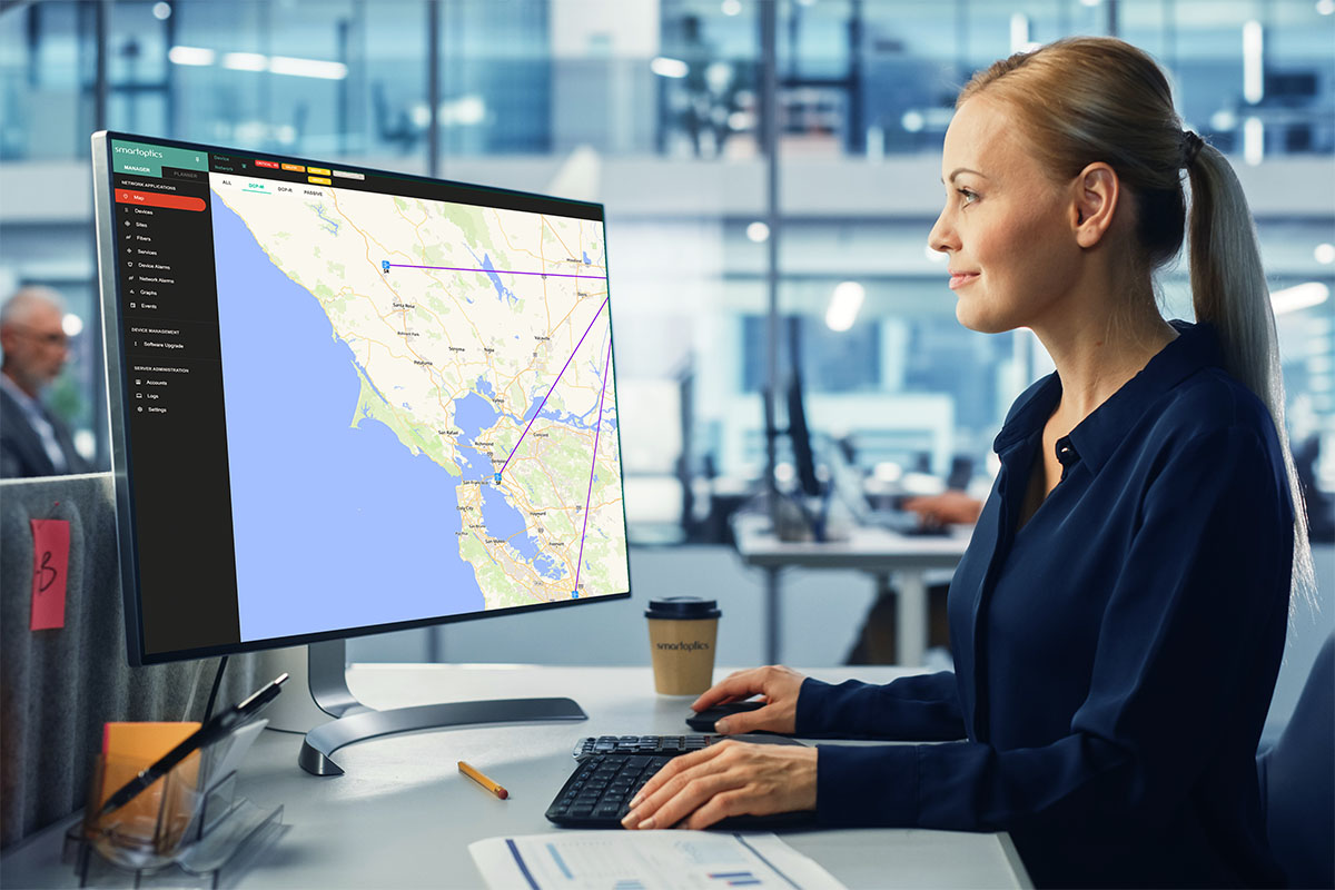Woman working at a desk, looking at a computer monitor displaying a digital map in a modern office.